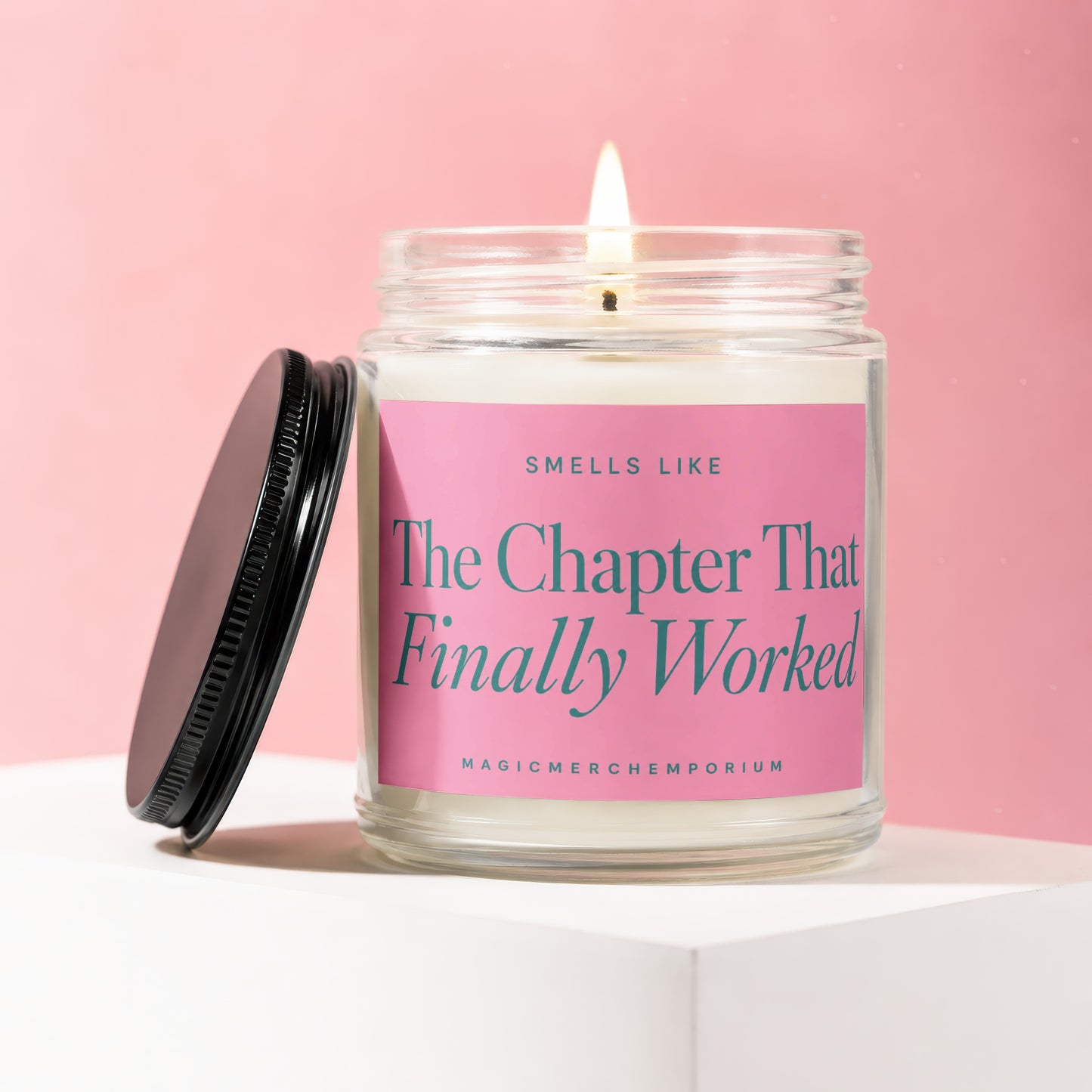 Jar candle with a lit wick and pink label that reads "Smells Like The Chapter That Finally Worked".
