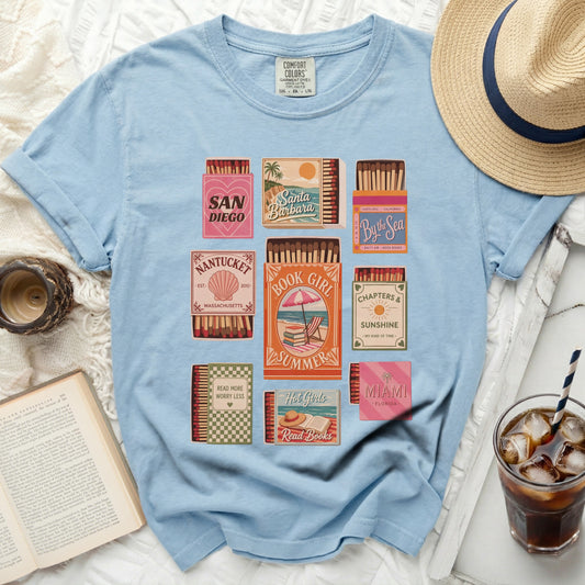 T-shirt featuring retro matchboxes with book and beach-themed sayings.