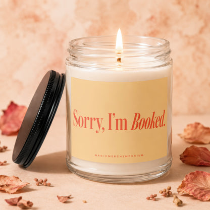 Glass jar candle with lit wick and label that reads "Sorry, I'm Booked."