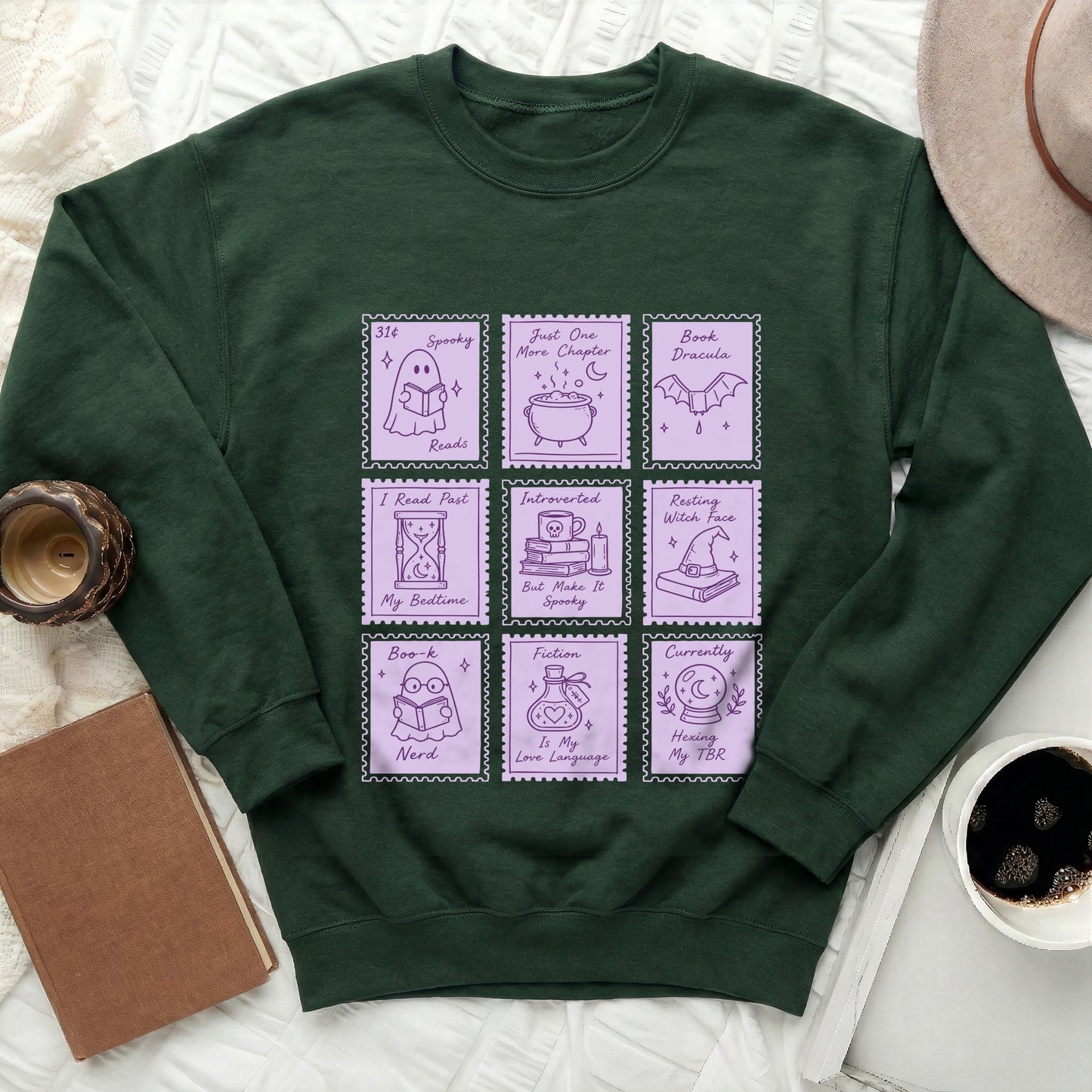 Dark green sweatshirt with purple stamp graphics about reading and spooky themes.
