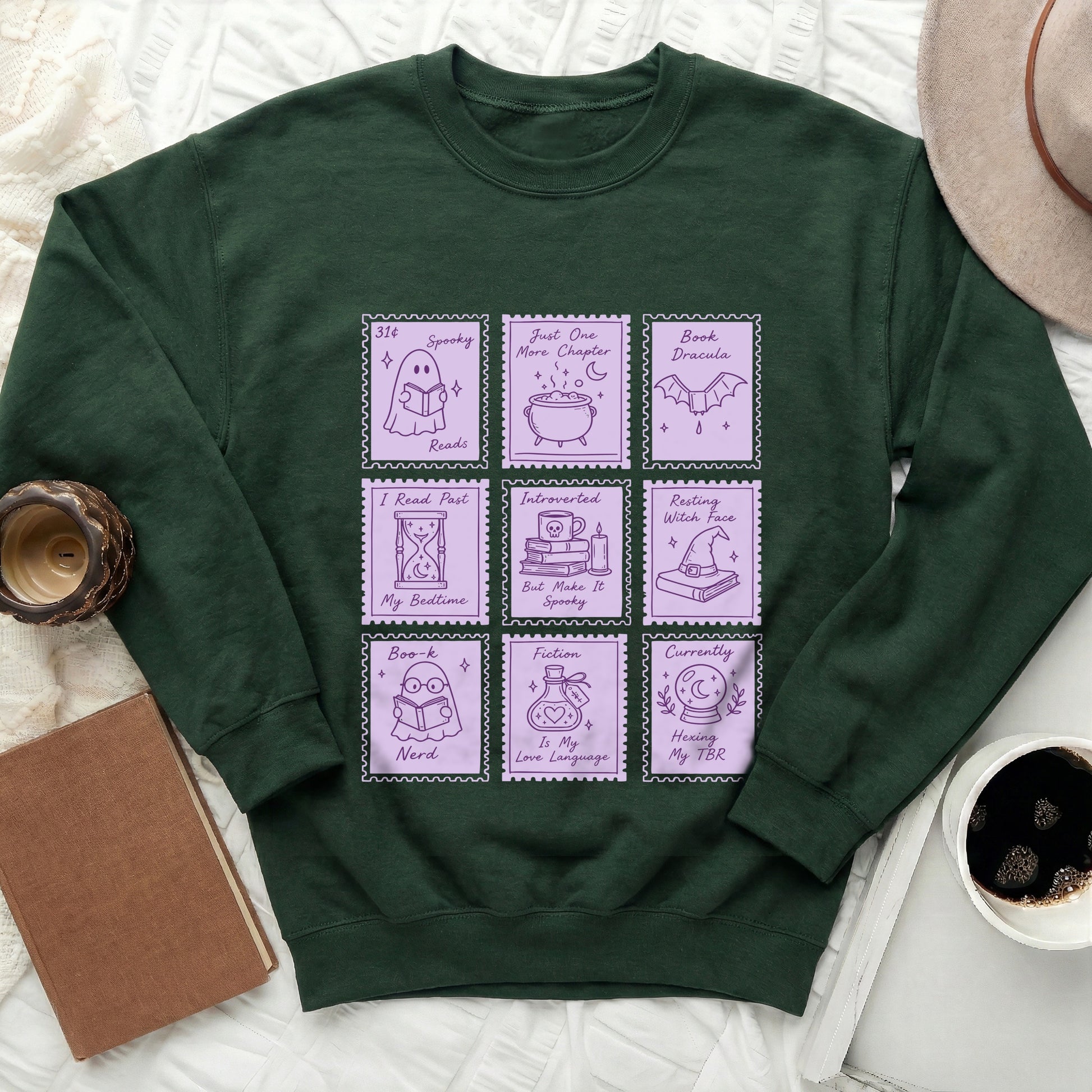 Dark green sweatshirt with purple stamp graphics about reading and spooky themes.