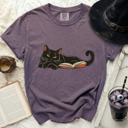 Purple t-shirt with black cat lying on an open book design.