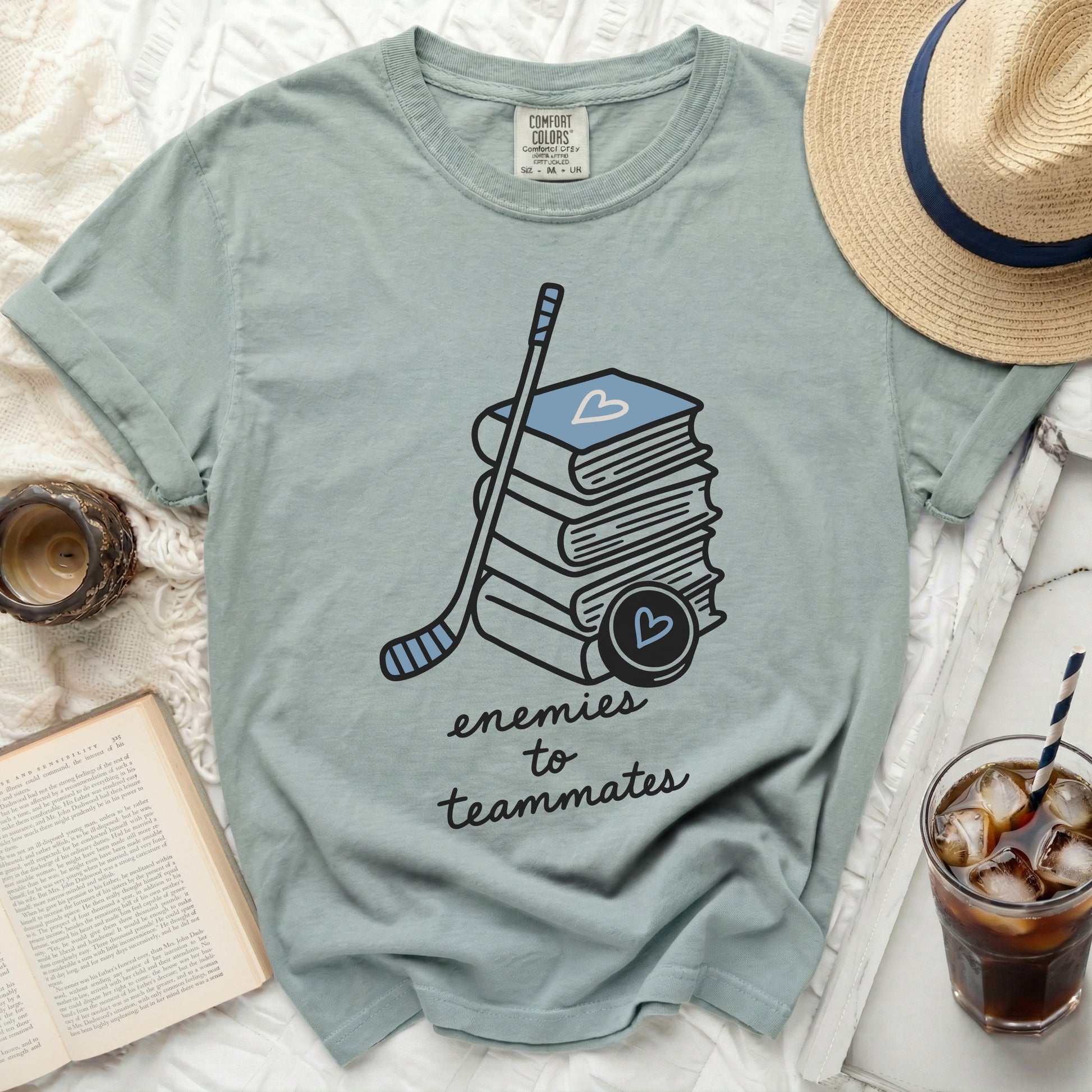 T-shirt with stack of books, hockey stick, and "enemies to teammates" text.