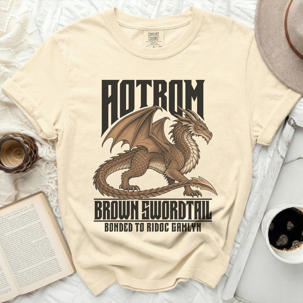 Cream t-shirt with a brown dragon graphic and text "AOTROM BROWN SWORDTAIL BONDED TO RIDOC GAMLYN".