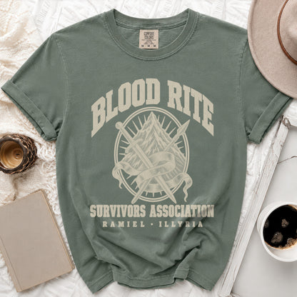 A muted green short-sleeve t-shirt with a graphic of crossed swords, a mountain, and text reading "Blood Rite Survivors Association Ramiel Illyria".