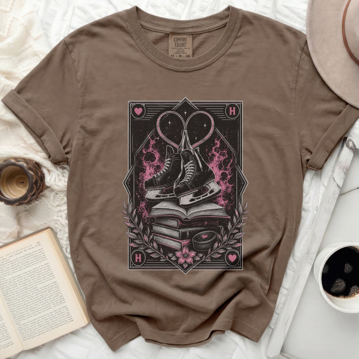 Brown t-shirt with stacked books, ice skates, and heart graphic.