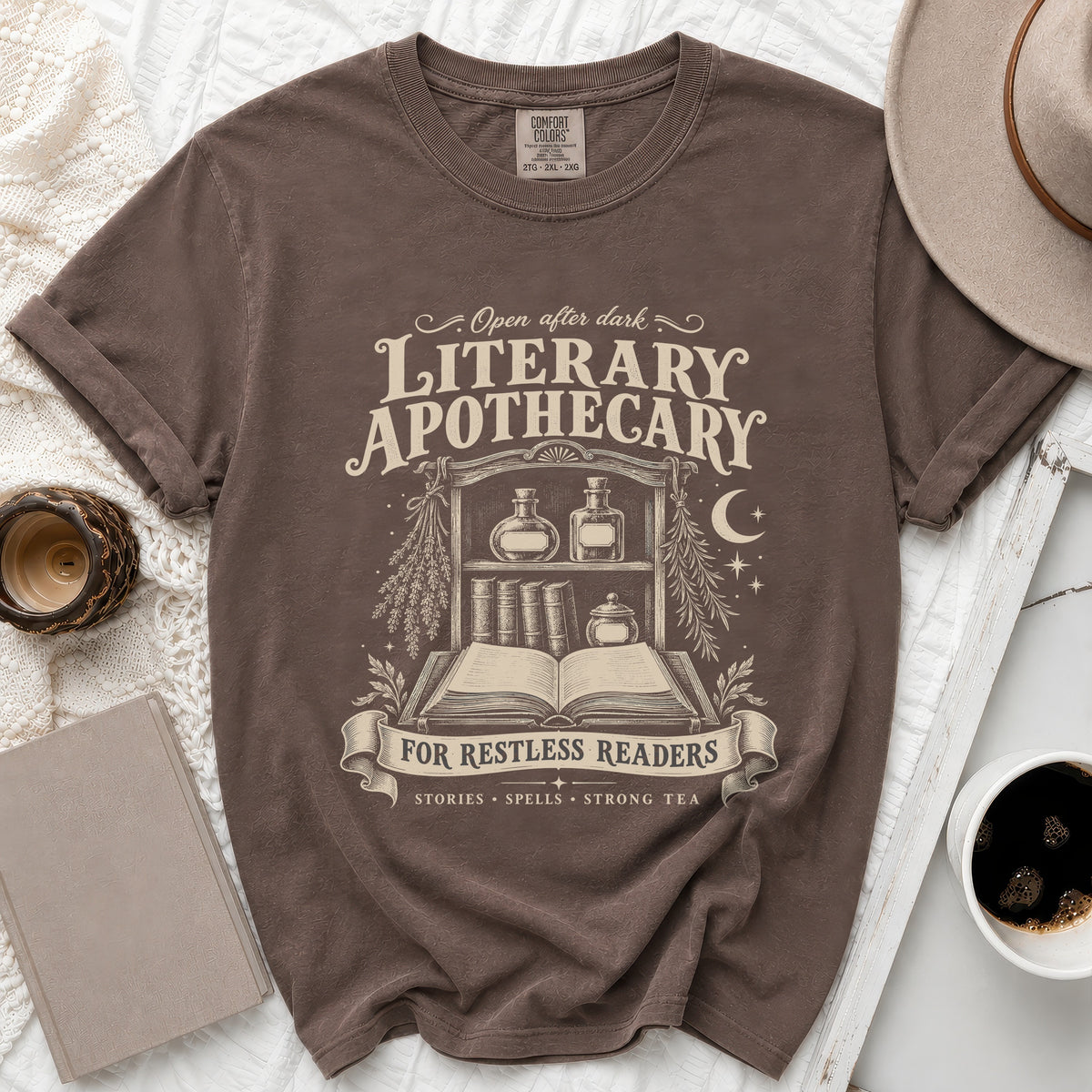 Brown t-shirt with Literary Apothecary graphic: open book, shelves, bottles, and text.