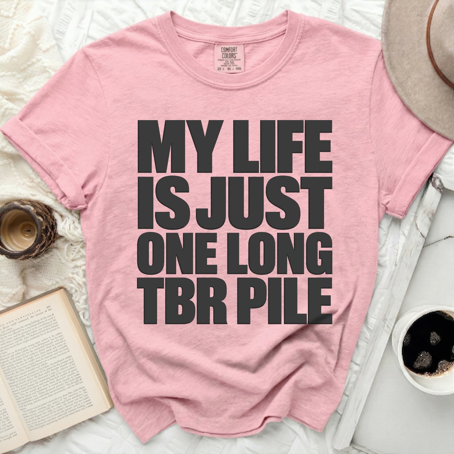 Pink t-shirt with black text "MY LIFE IS JUST ONE LONG TBR PILE".