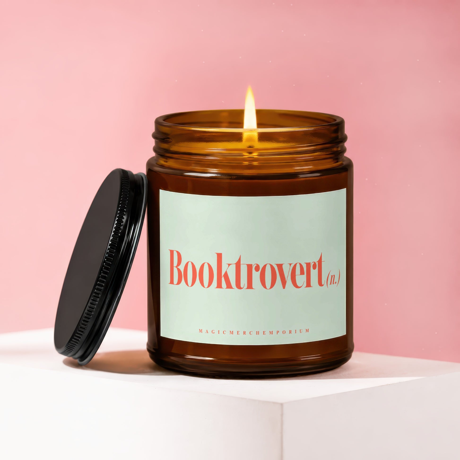 Amber jar candle with lit flame and "Booktrovert (n.)" text.