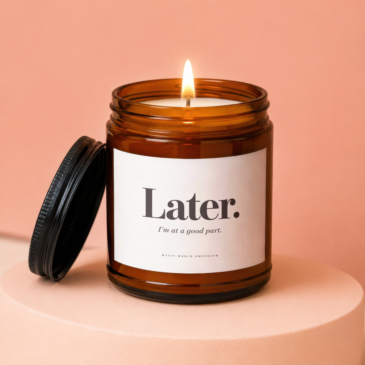 Amber jar candle with lit wick, reads "Later. I'm at a good part."