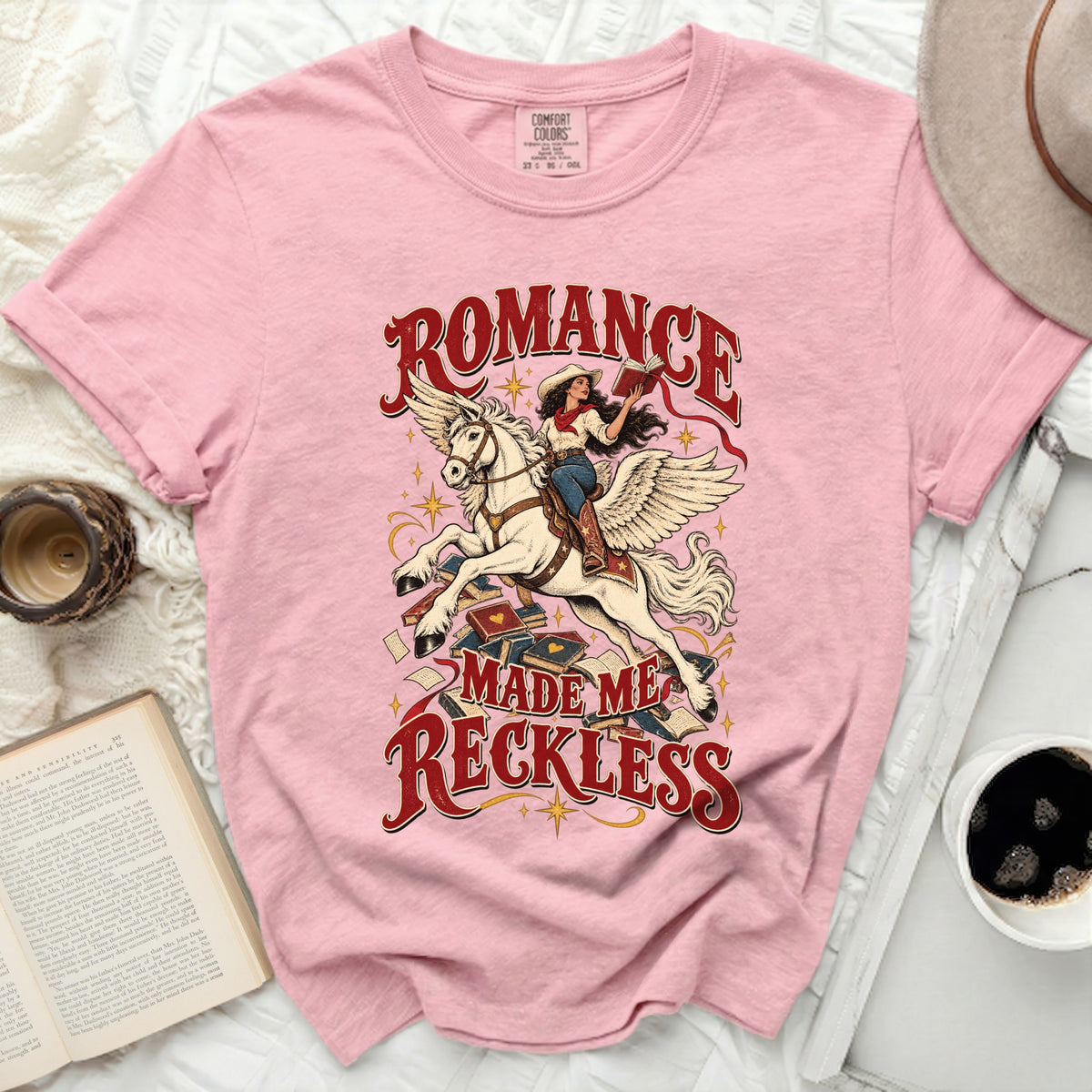 Pink t-shirt with "Romance Made Me Reckless" graphic featuring a woman on a winged horse.
