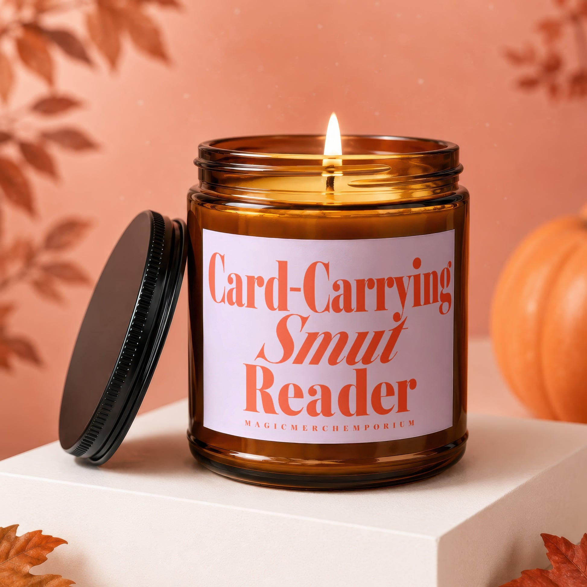 Candle with label "Card-Carrying Smut Reader" on a pedestal with pumpkin.
