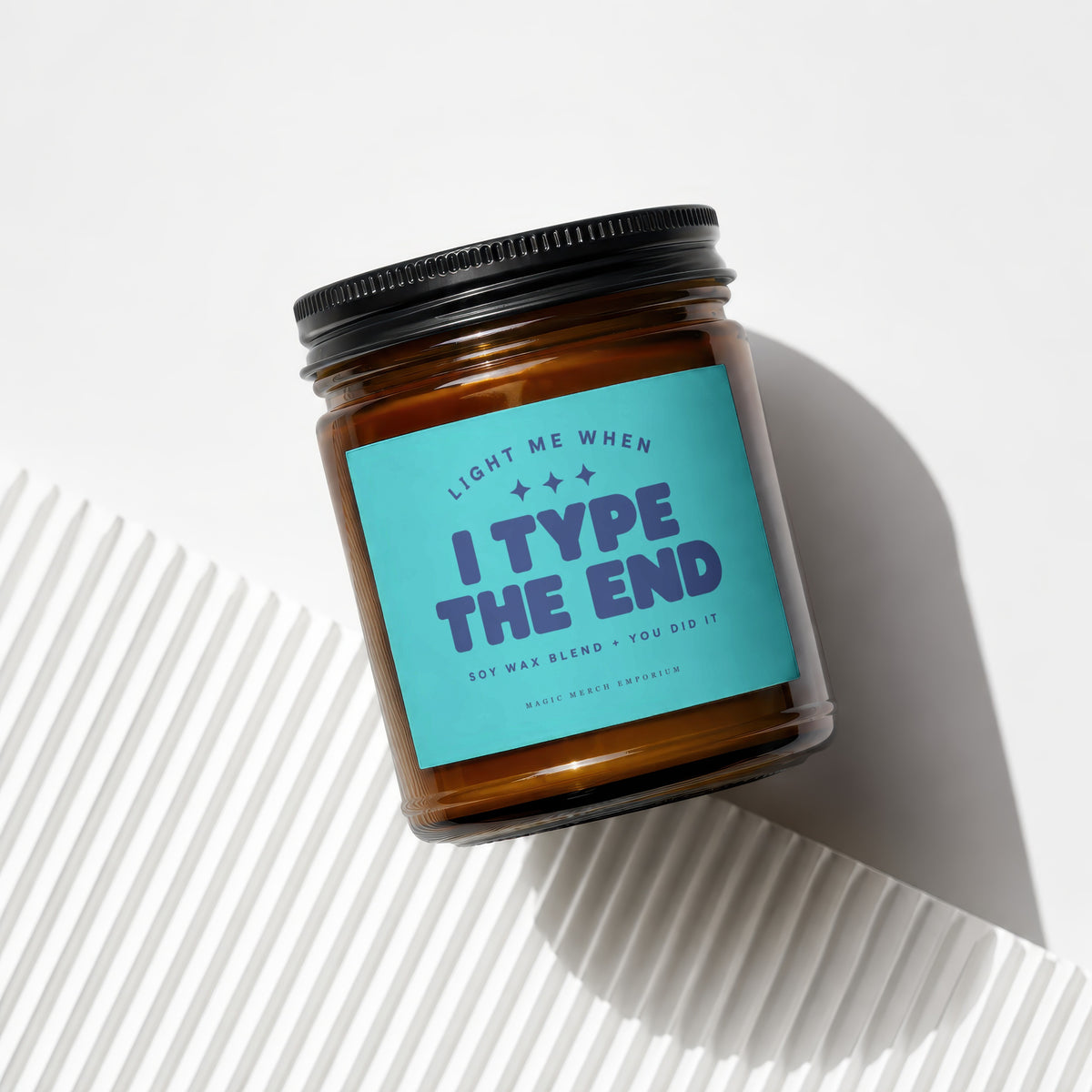 Amber candle with turquoise label reading "Light me when I Type The End".