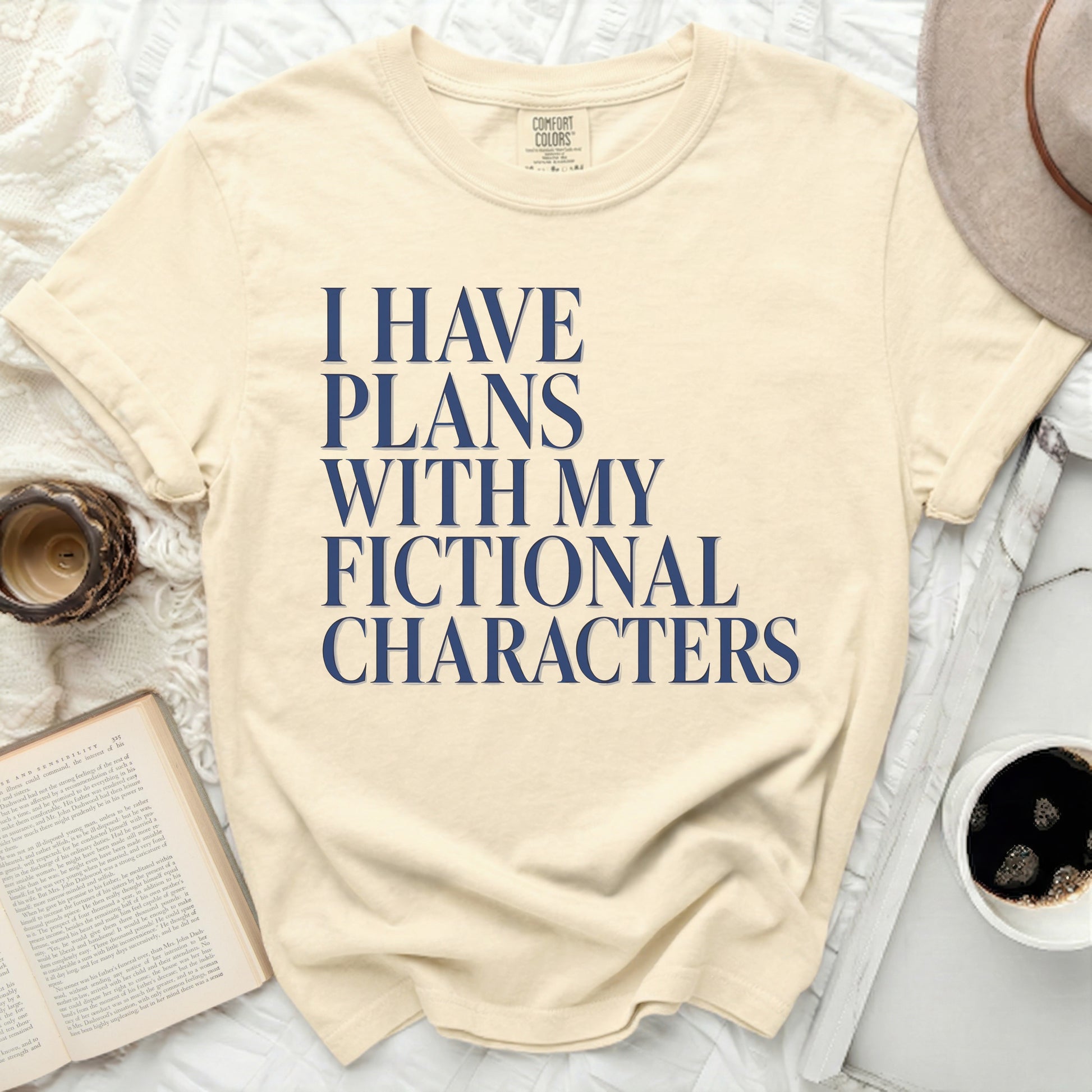 Cream t-shirt with navy blue text reading "I HAVE PLANS WITH MY FICTIONAL CHARACTERS."