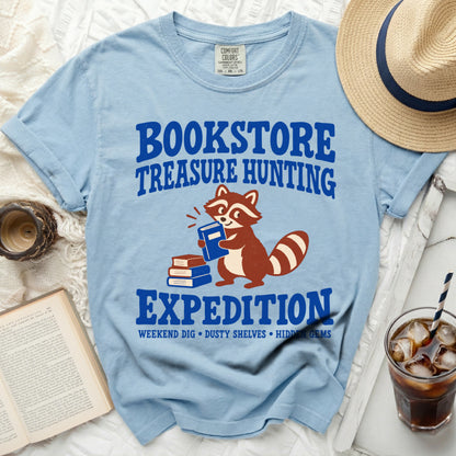 Light blue t-shirt with "BOOKSTORE TREASURE HUNTING EXPEDITION" and a raccoon graphic.