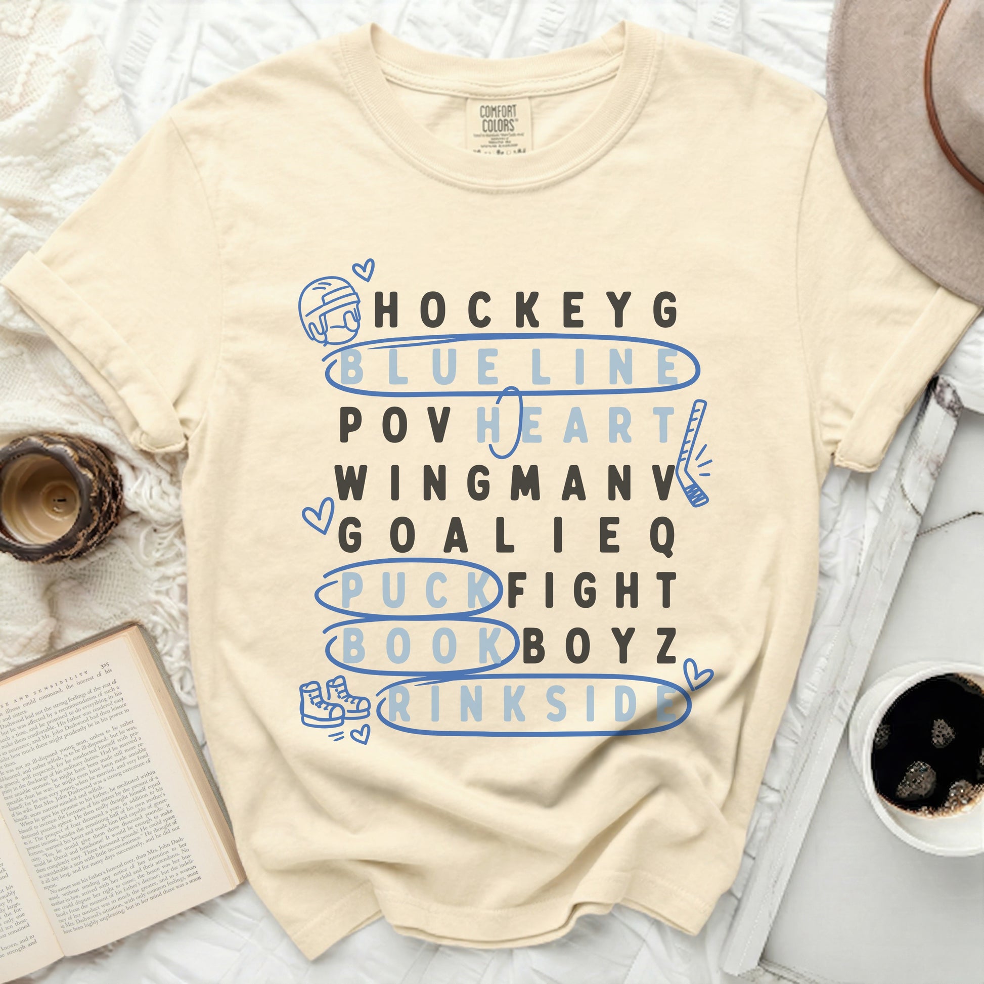 Cream t-shirt with hockey-themed word art: Hockey, Blueline, Heart, Wingman, Goalie, Puck Fight, Drinksid.