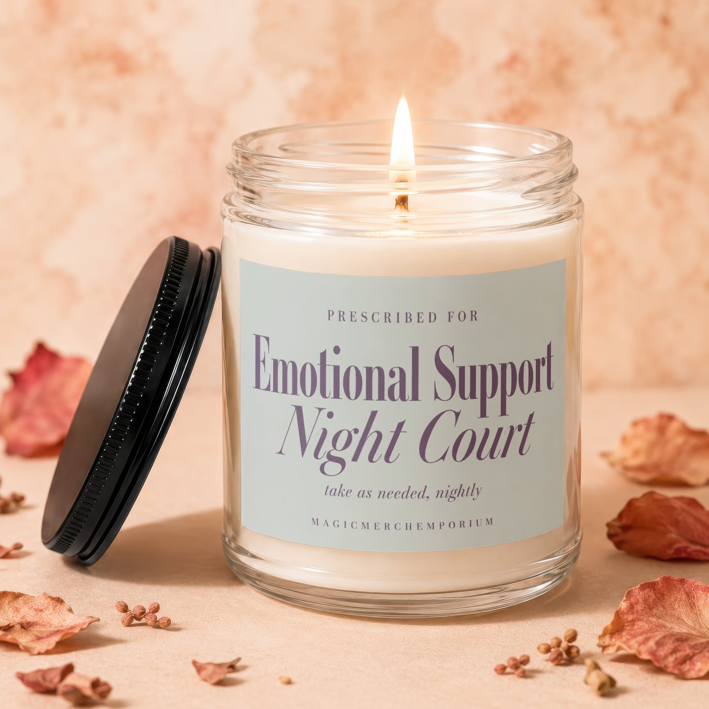 Candle labeled "Emotional Support Night Court" with lit wick, lid off.
