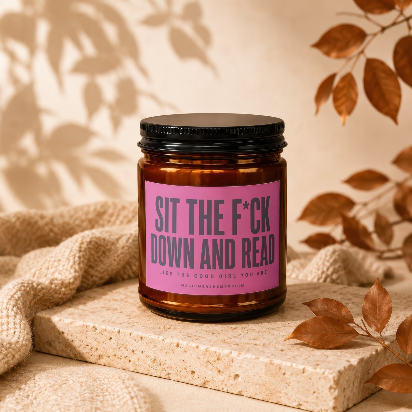 Amber candle with pink label reading "Sit the F*ck Down and Read".