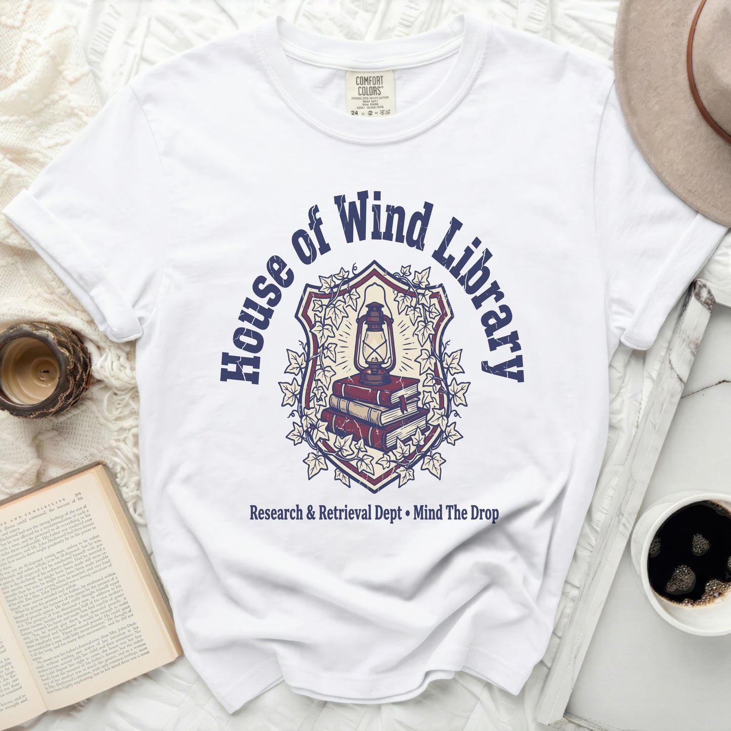 White t-shirt with "House of Wind Library" crest graphic and text.