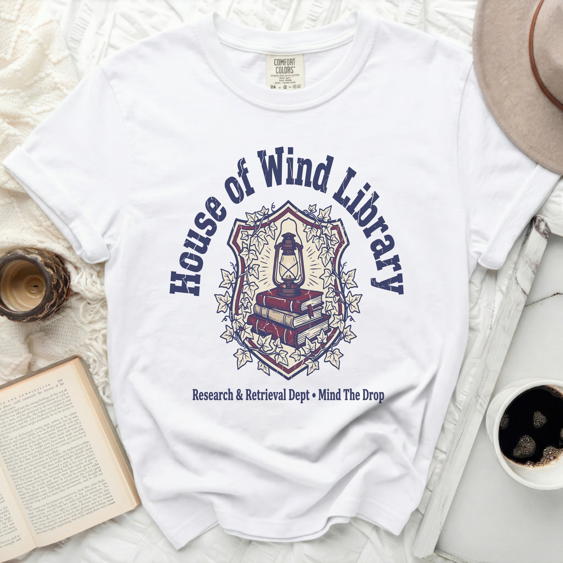 White t-shirt with "House of Wind Library" crest graphic and text.