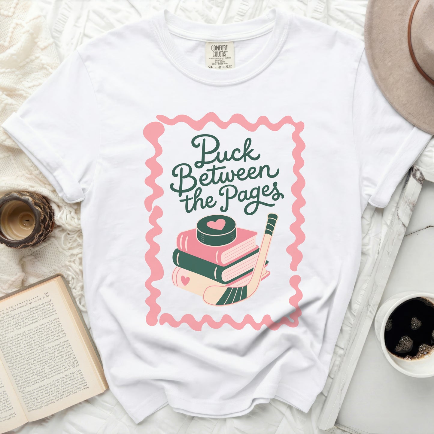 White t-shirt with "Puck Between the Pages" text and hockey puck.