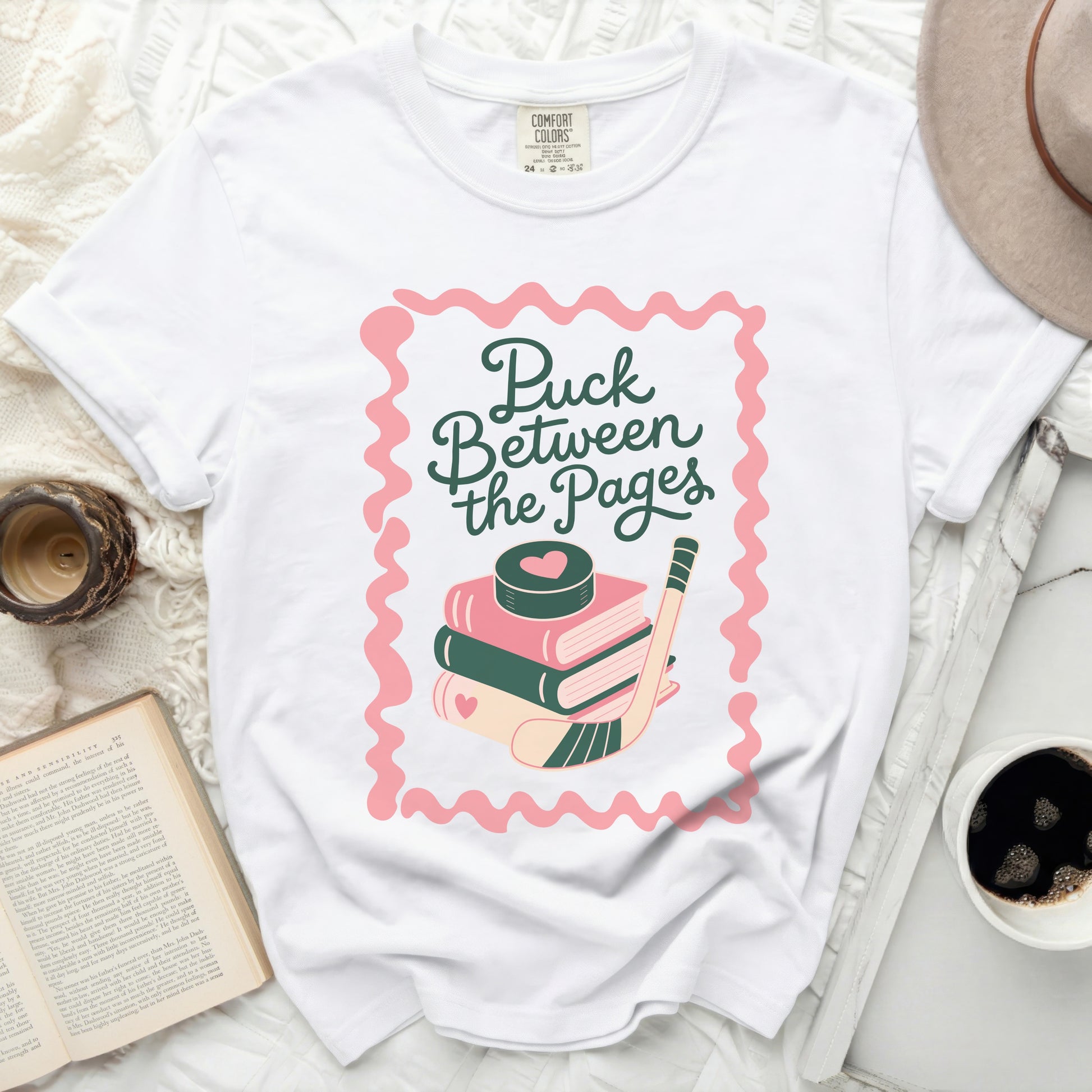 White t-shirt with "Puck Between the Pages" text and hockey puck.