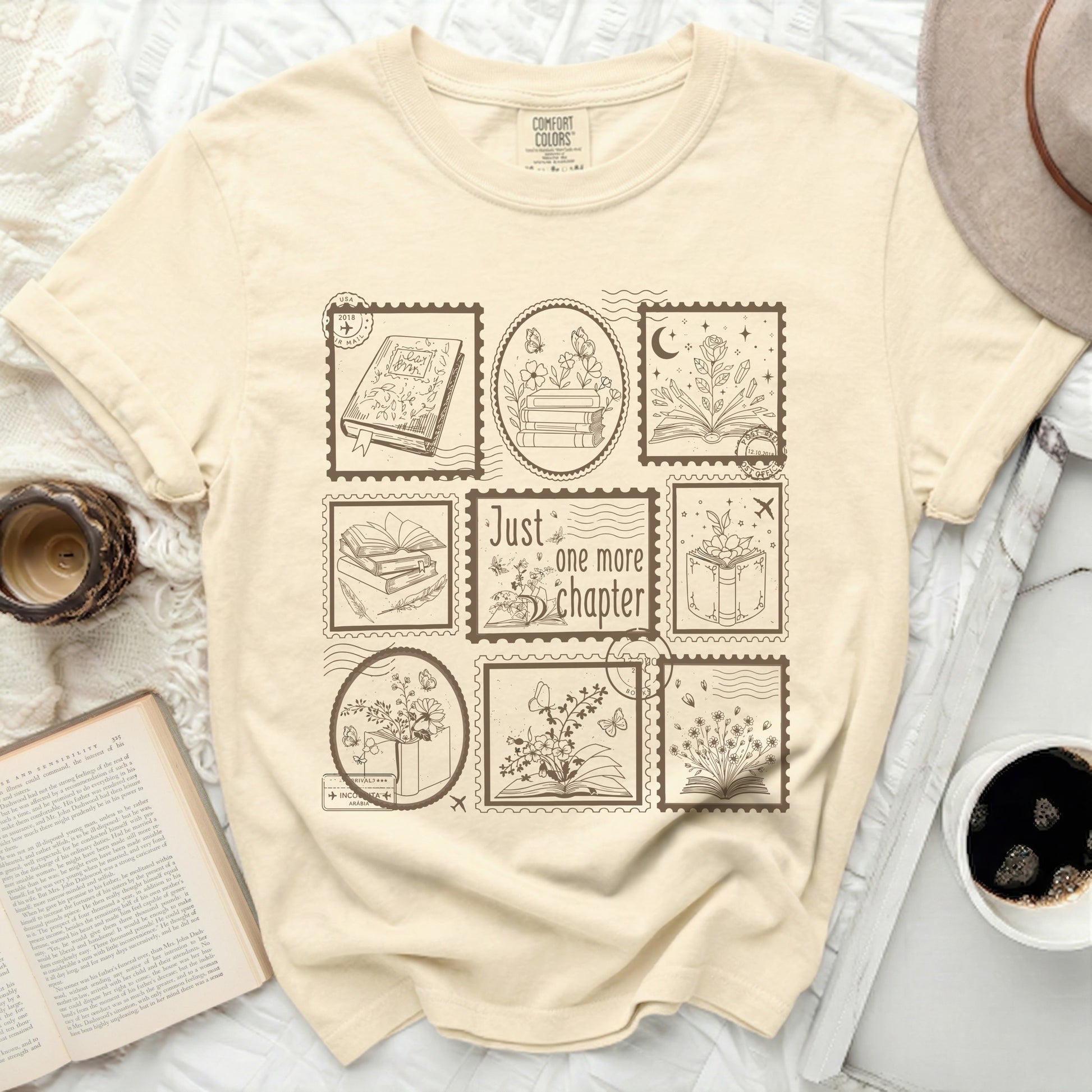 Cream t-shirt with stamp designs featuring books, flowers, and butterflies.