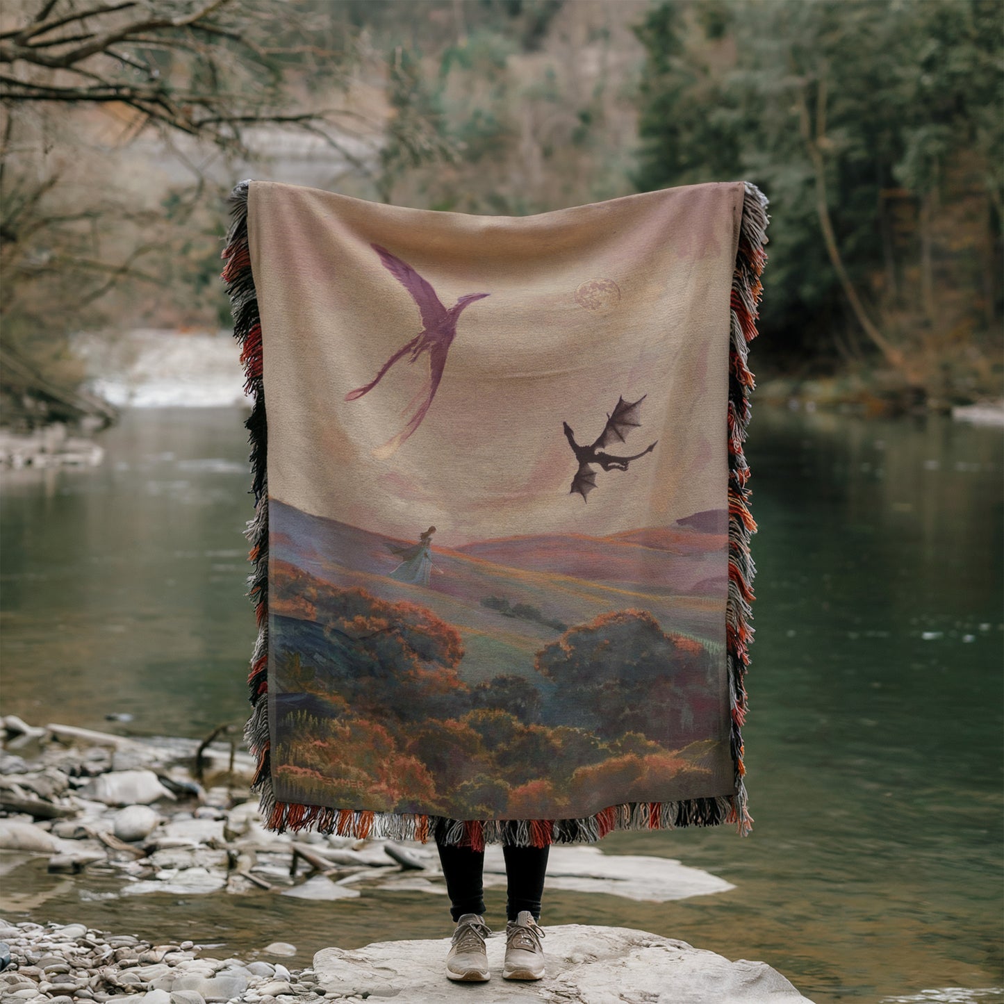 A person stands on a rock, holding a large blanket with a painting of a landscape featuring a dragon and a woman.