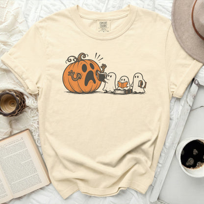 Cream t-shirt with a graphic of a surprised pumpkin and three ghosts reading books.