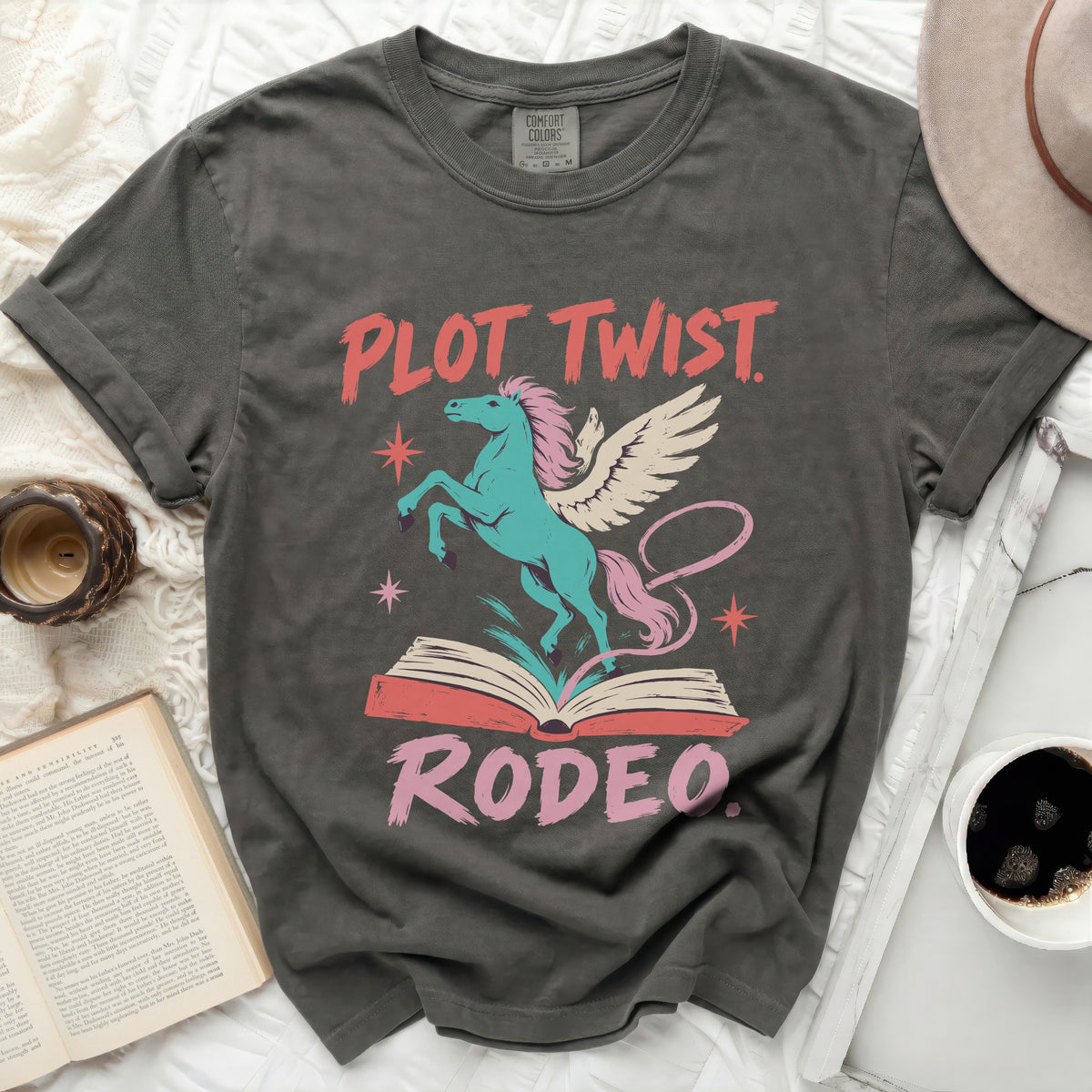 Grey t-shirt with "Plot Twist Rodeo" text and a winged unicorn on an open book.