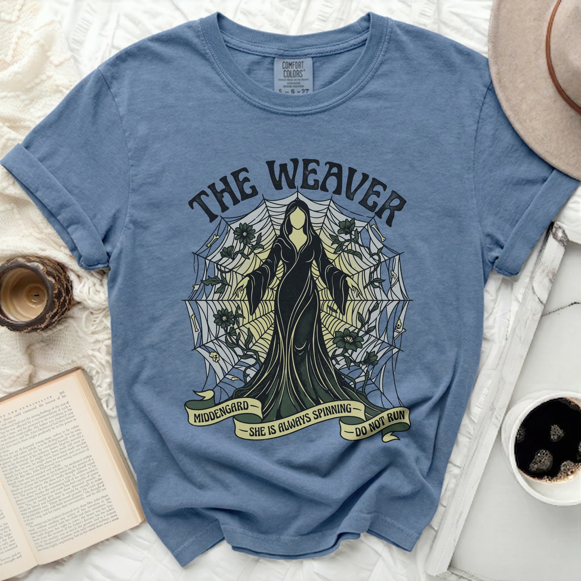 Blue t-shirt with "The Weaver" and spiderweb graphic; "Middengard She is Always Spinning Do Not Run".