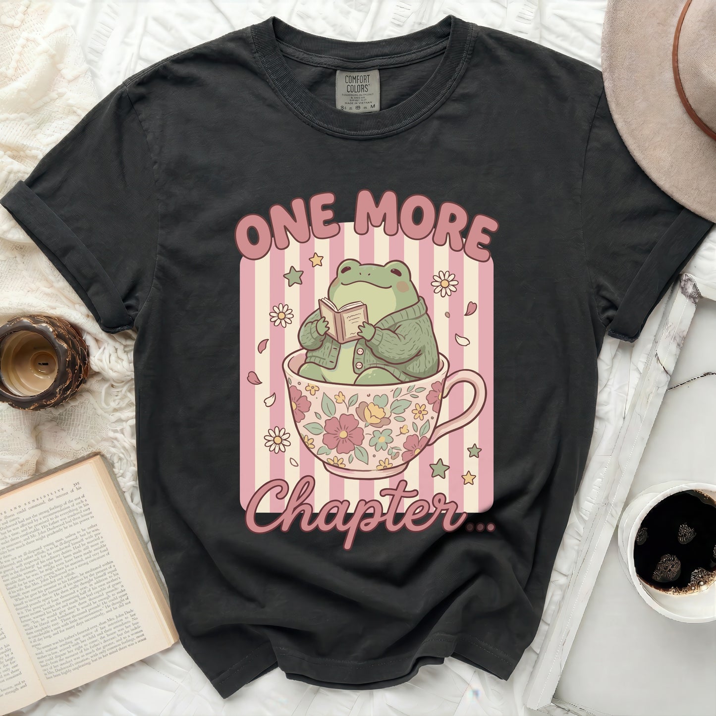Frog in a teacup reading a book with text "One More Chapter".