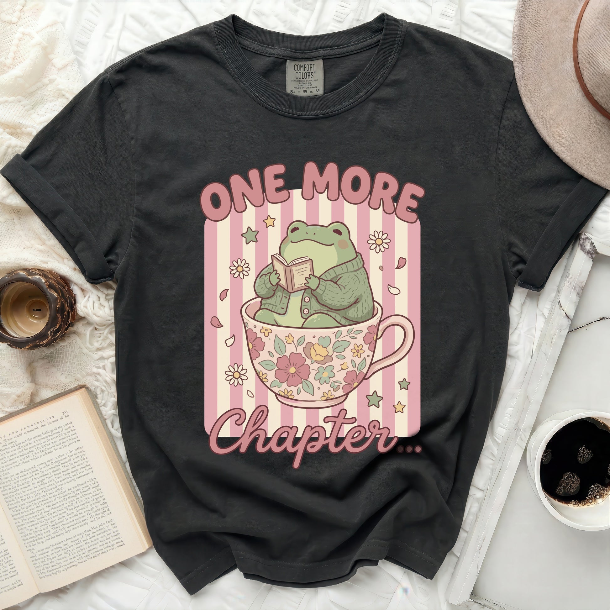 Frog in a teacup reading a book with text "One More Chapter".