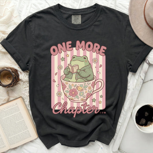 Frog in a teacup reading a book with text "One More Chapter".