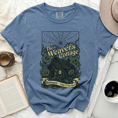 The Weaver's Cottage shirt features a dark cottage design with vines and spiderwebs.