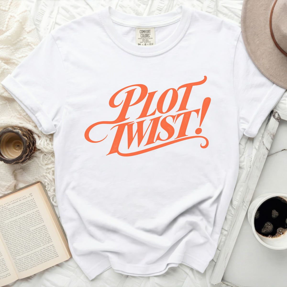 White Comfort Colors t-shirt with orange "Plot Twist!" graphic.