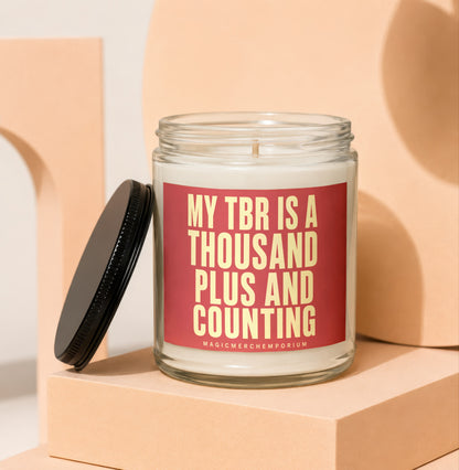 Glass candle with red label reading "MY TBR IS A THOUSAND PLUS AND COUNTING".