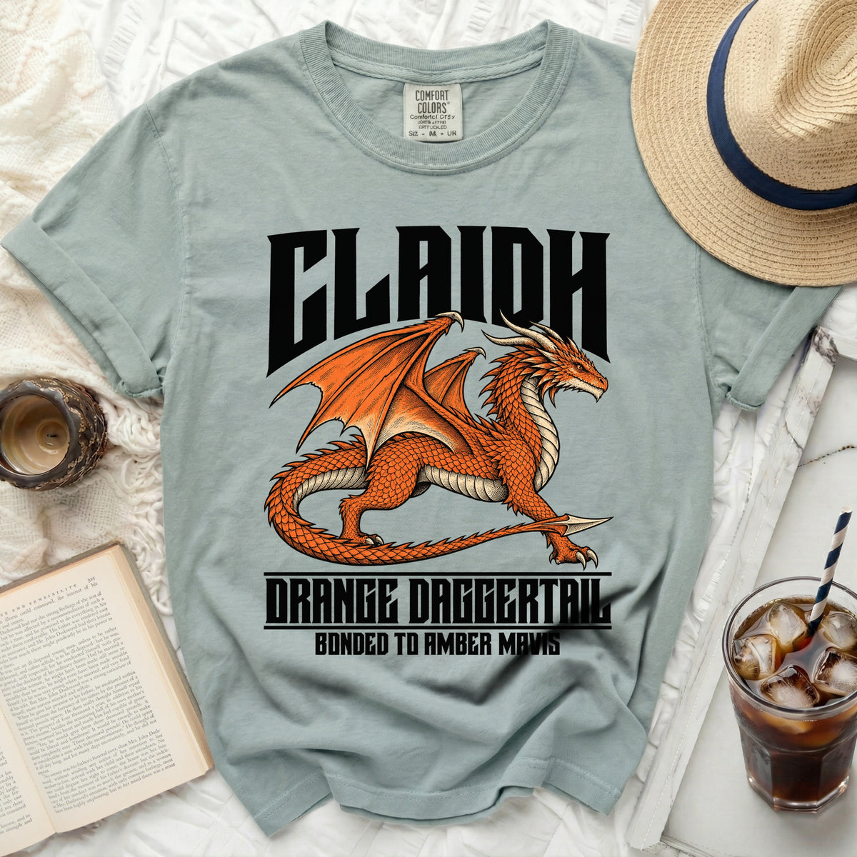 Light blue t-shirt with a black dragon and text "CLAIDH ORANGE DAGGERTAIL BONDED TO AMBER MAVIS".