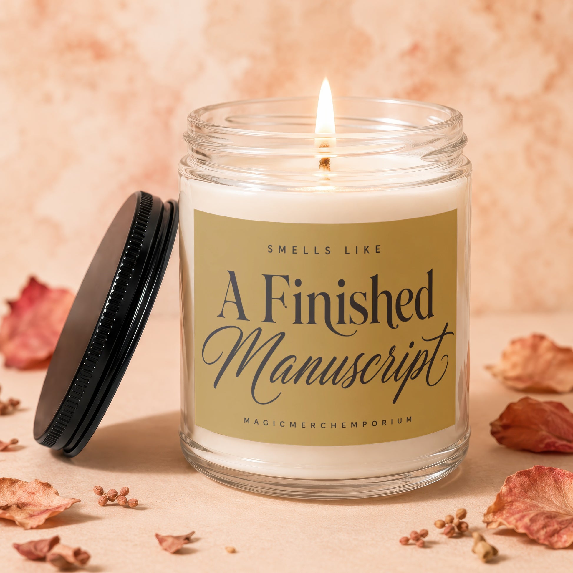 Lit glass candle with gold label reading "A Finished Manuscript" and "Smells Like".