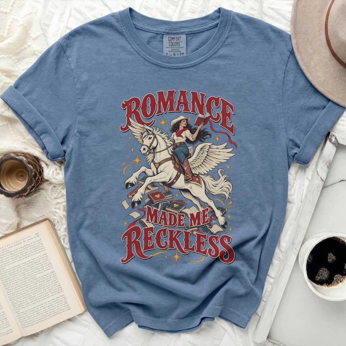 Blue t-shirt with "Romance Made Me Reckless" text and a woman on a Pegasus.
