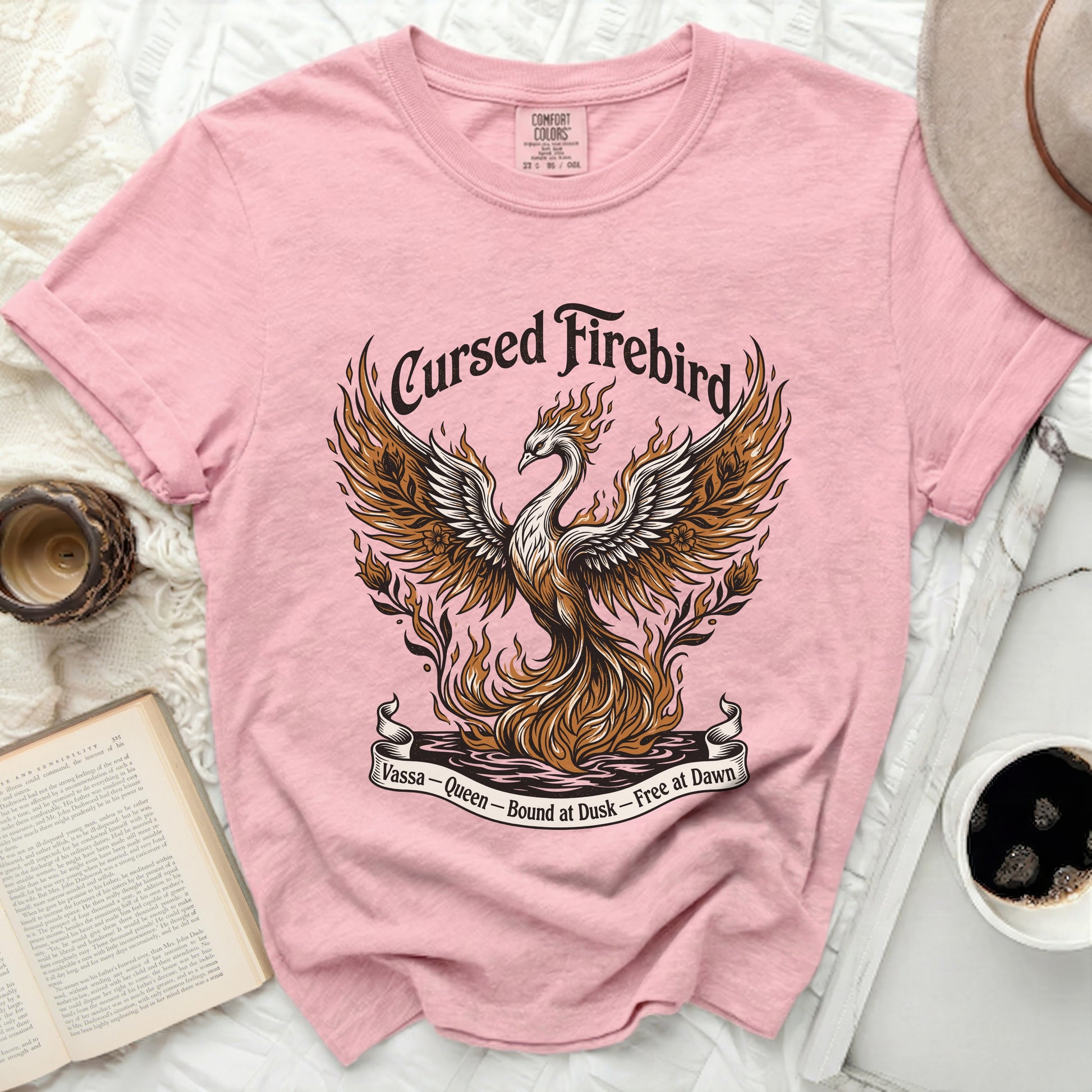 Pink t-shirt with a "Cursed Firebird" graphic and text "Vassa - Queen - Bound at Dusk - Free at Dawn".