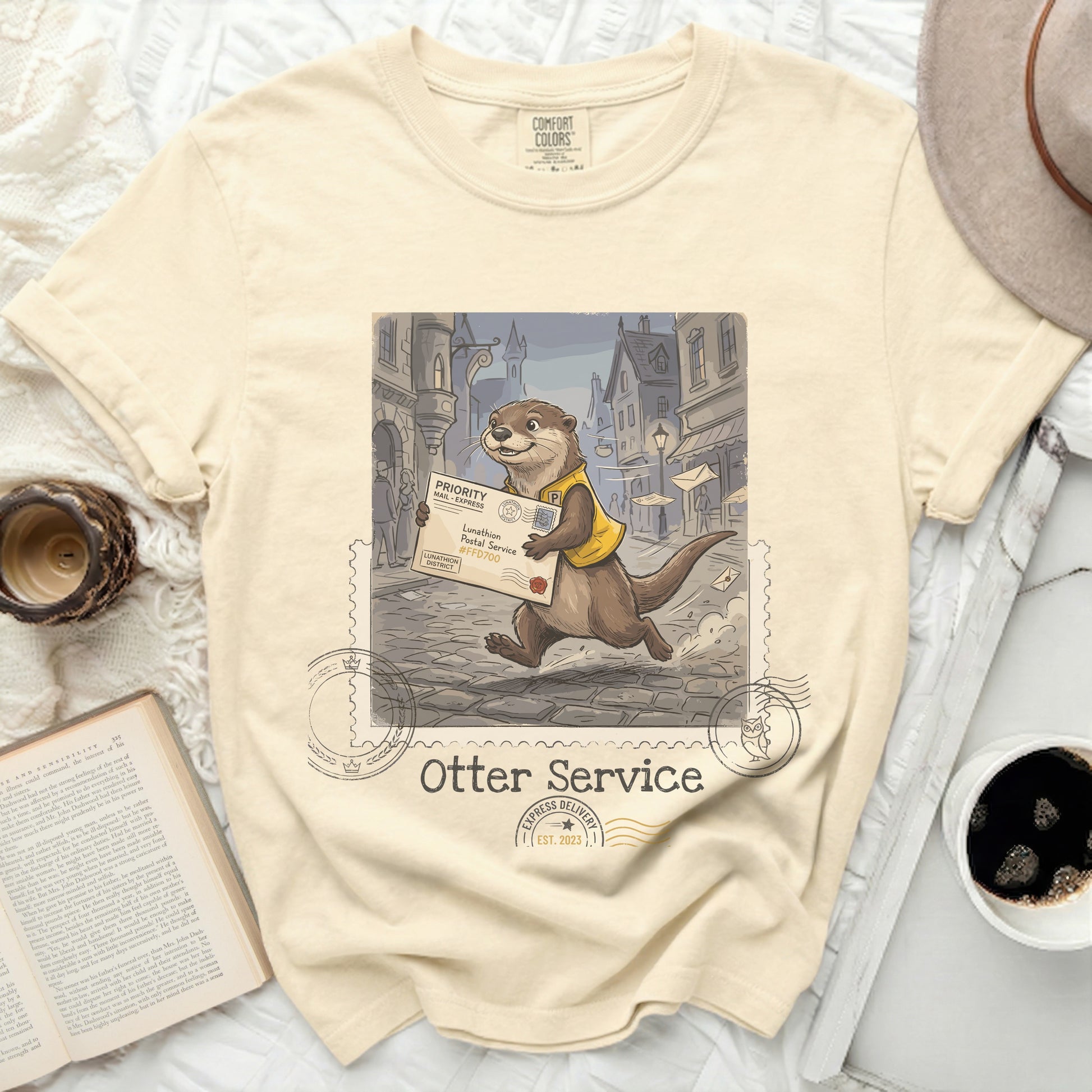 Cream t-shirt with an illustration of an otter delivering mail.