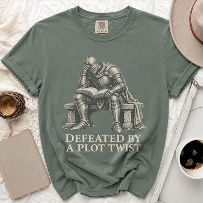 T-shirt with illustration of knight reading a book with text "Defeated by a plot twist".