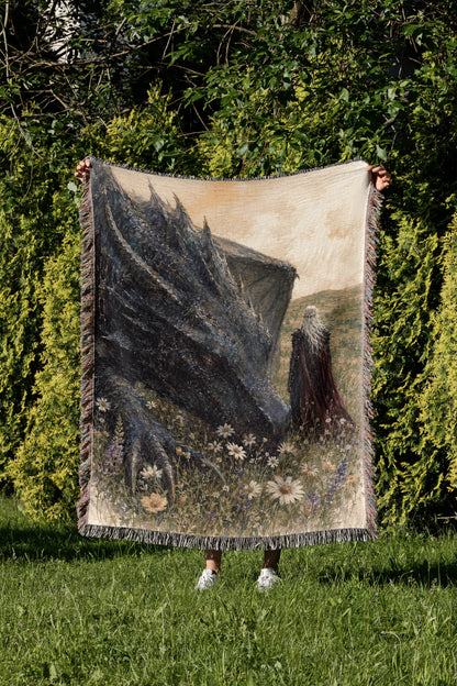 A person is holding up a large tapestry depicting a dragon in a grassy field with flowers.