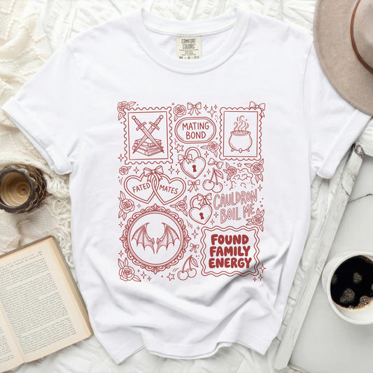 White t-shirt with red line art designs including swords, cauldron, hearts, and text.