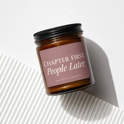 Amber glass candle with black lid and pink label reading "Chapter First. People Later."