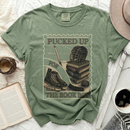 Green t-shirt with "Puckered Up For The Book Boy" hockey and book design.