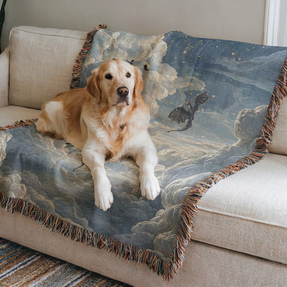 A golden retriever dog is lying on a couch with a blue and white blanket featuring a dragon and clouds on it.