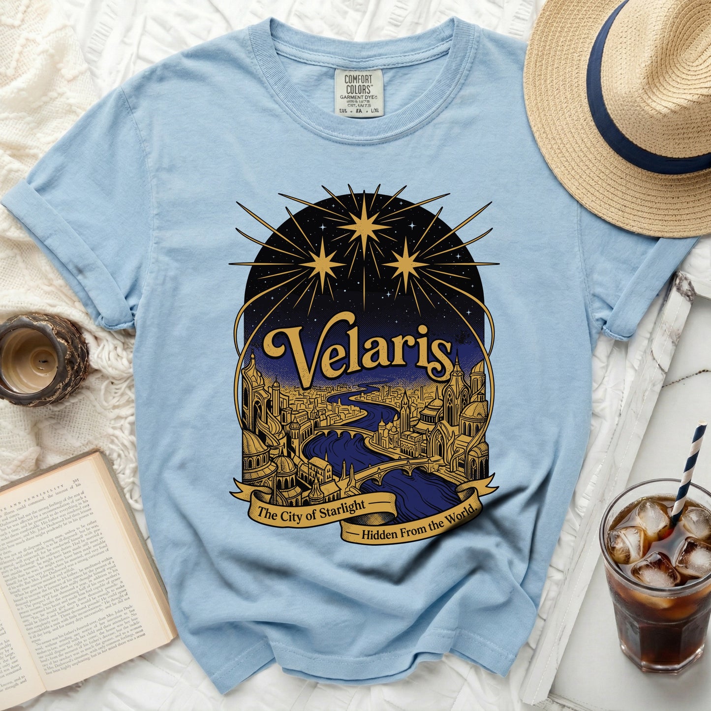 Light blue t-shirt with a graphic of Velaris, the City of Starlight.