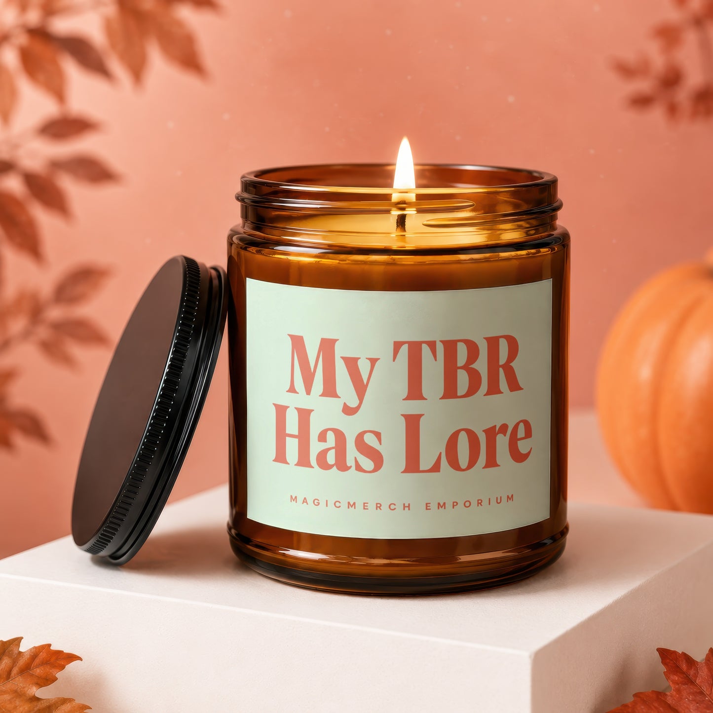 Amber jar candle with lit flame, "My TBR Has Lore" label, and a pumpkin.